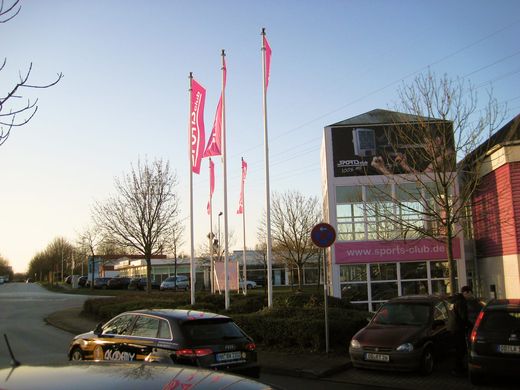 Rote Fahnen wehen an einem Fahnenmast vor einem Gebäude im Wind