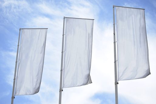 Drei weiße Flaggen mit Fahnenmast wehen im Wind vor blauem Himmel im Hintergrund